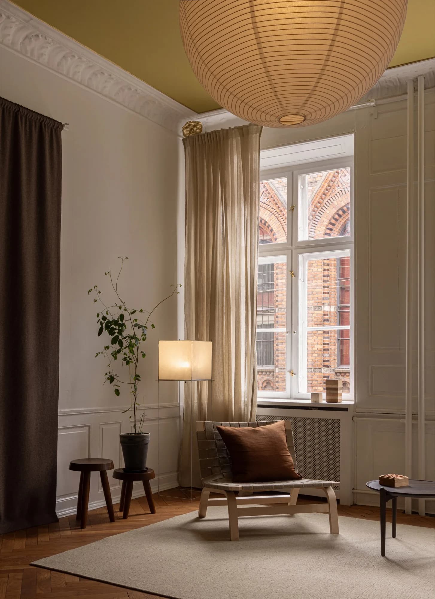 Hjørne af klinikken på Fiolstræde 14 med lænestol, gulvlampe og planter i varmt lys
