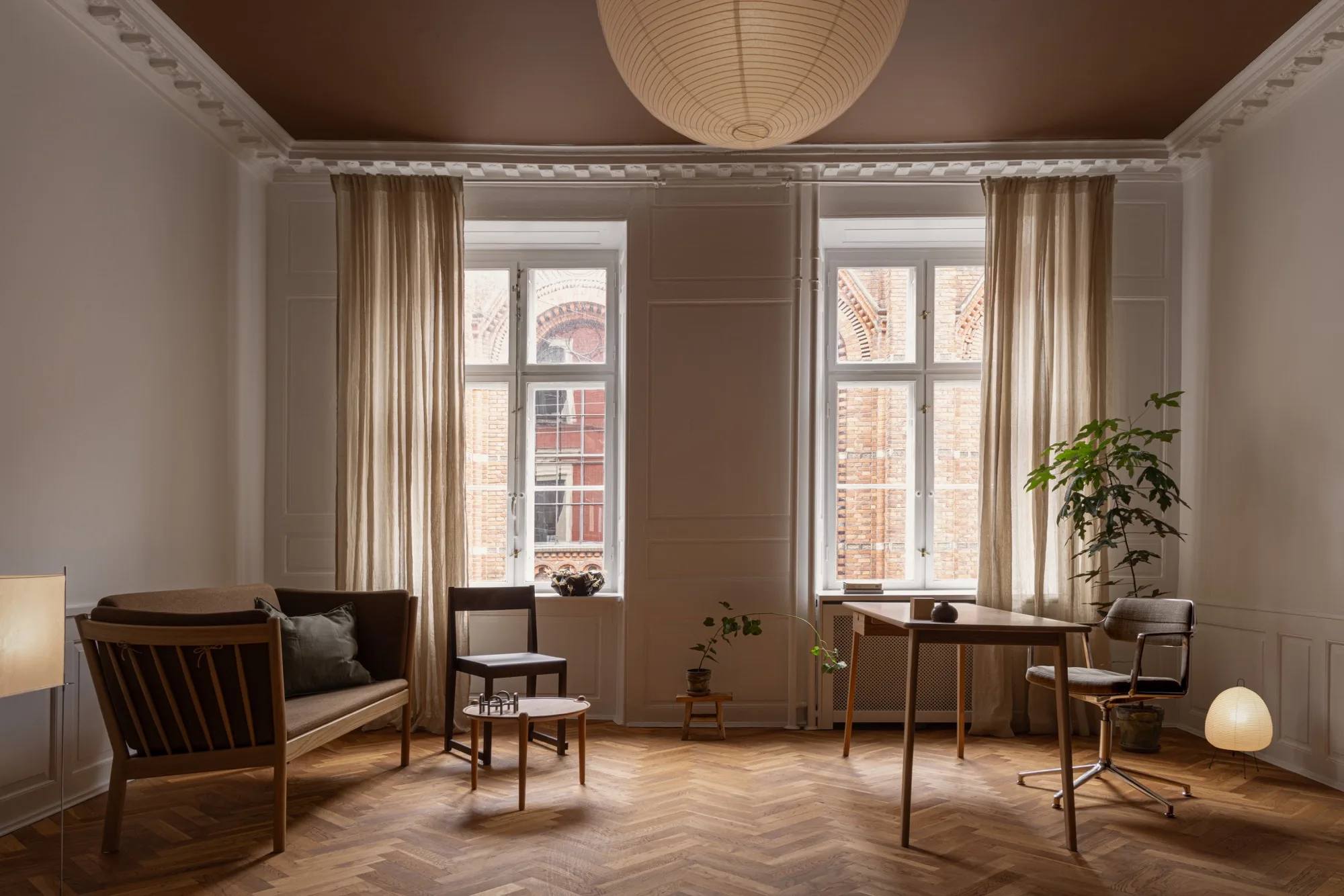 The consultation room at Fiolstræde 14: desk, chairs, and herringbone parquet in warm evening light