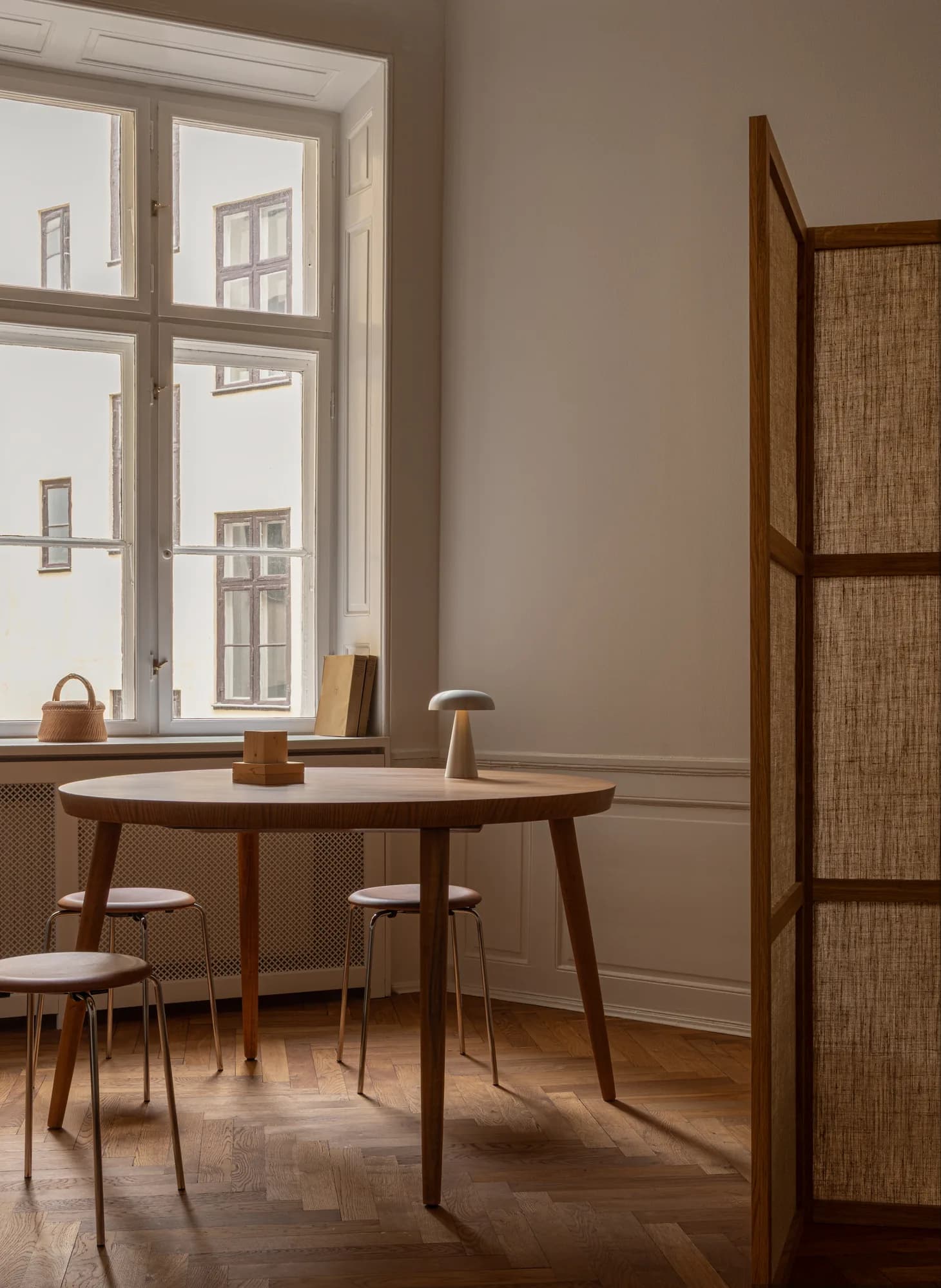 Meeting nook at Alethia, Fiolstræde 14, Copenhagen: round wooden table with stools, Akari table lamp and large windows facing the courtyard